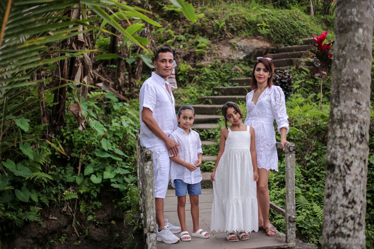 A family dressed in white make their way down stone steps through a garden