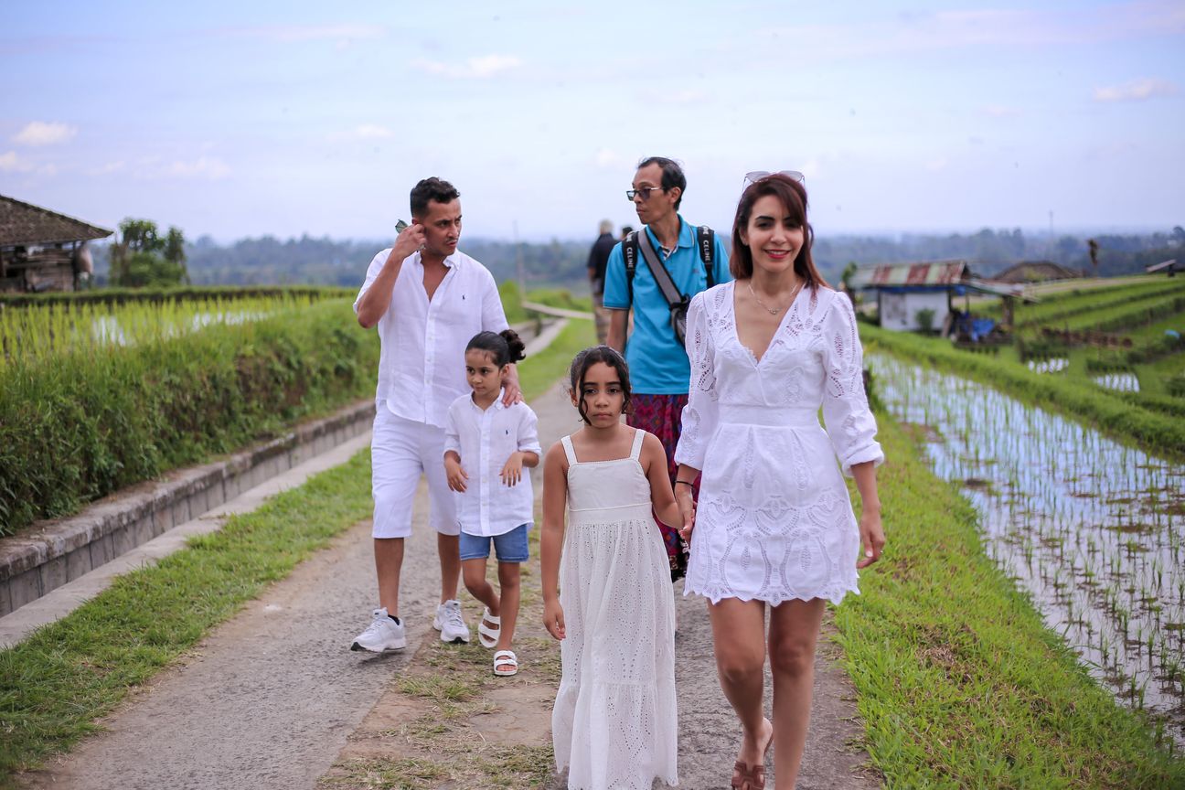 A family dressed in white walk the paths between the rice terraces