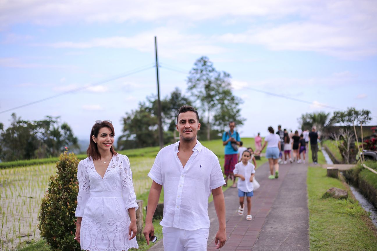 A family dressed in white walk the paths between the rice terraces