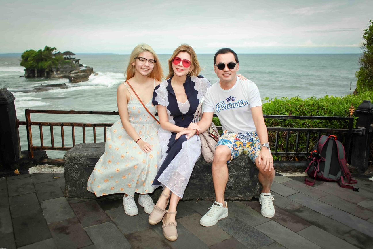 Three travellers pose together at a temple and coastal viewpoint in Bali
