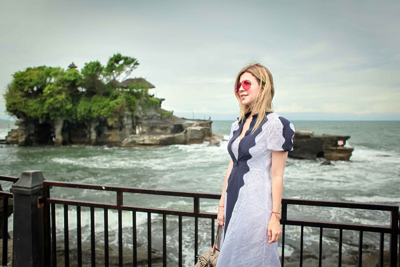 Three travellers pose together at a temple and coastal viewpoint in Bali
