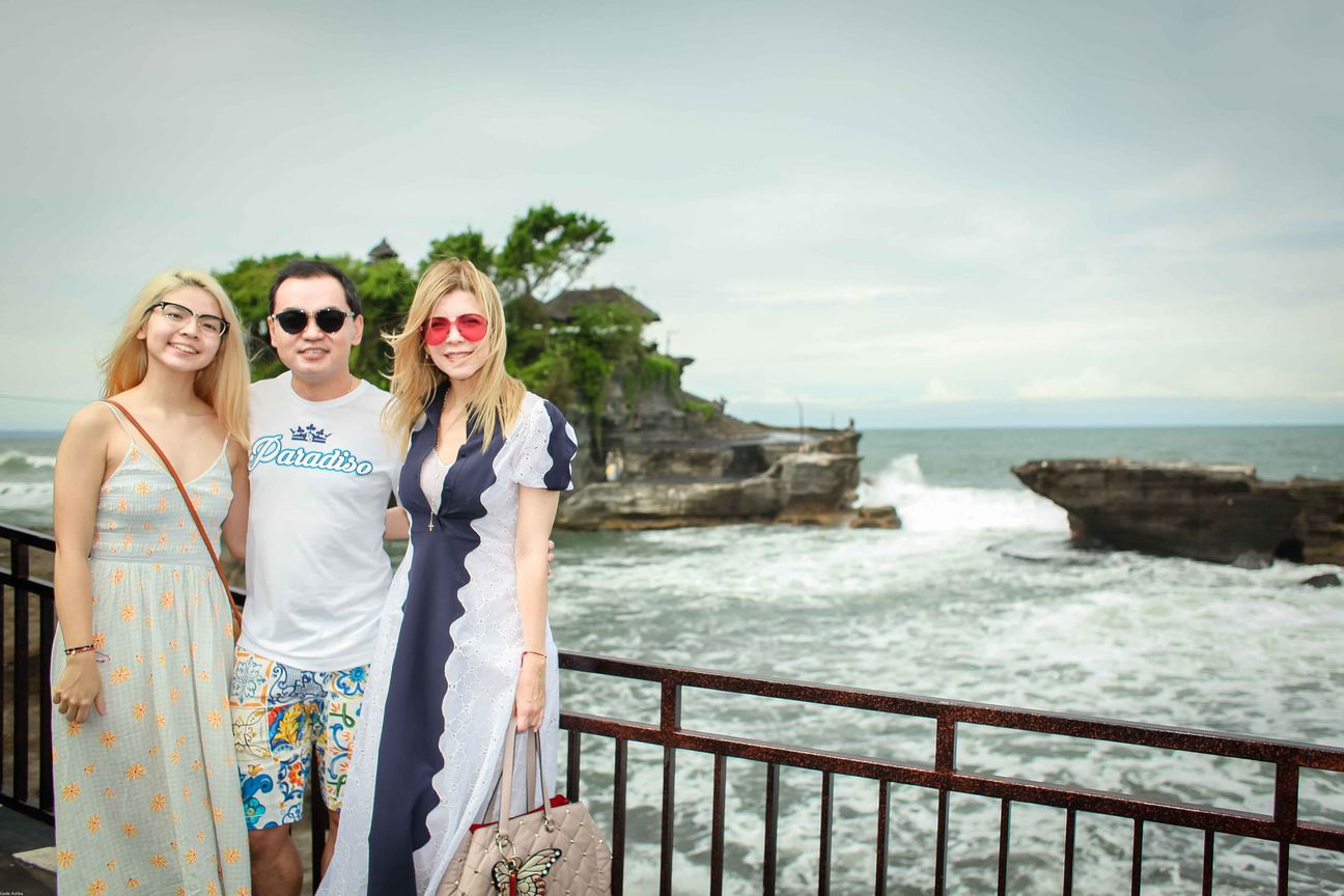 Three travellers pose together at a temple and coastal viewpoint in Bali