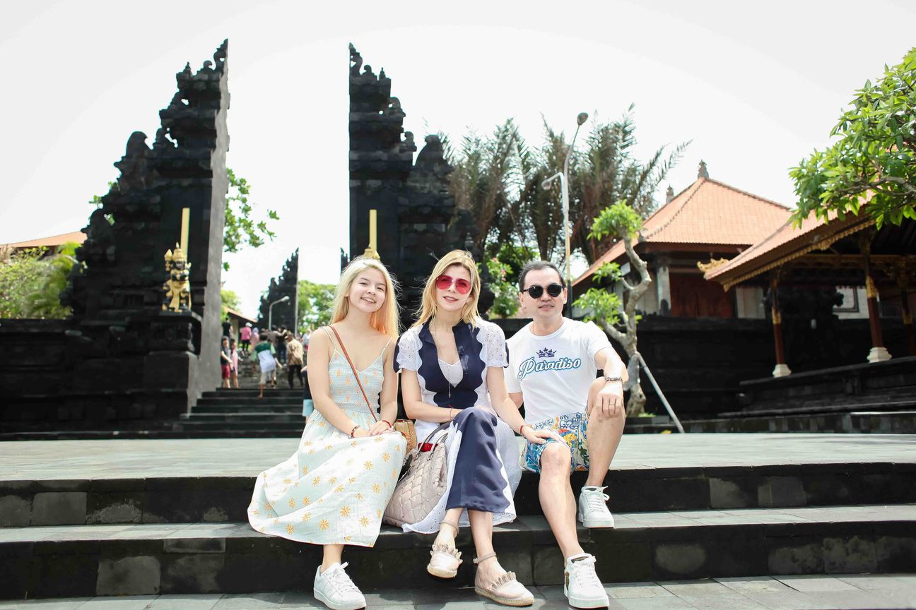 Three travellers pose together at a temple and coastal viewpoint in Bali