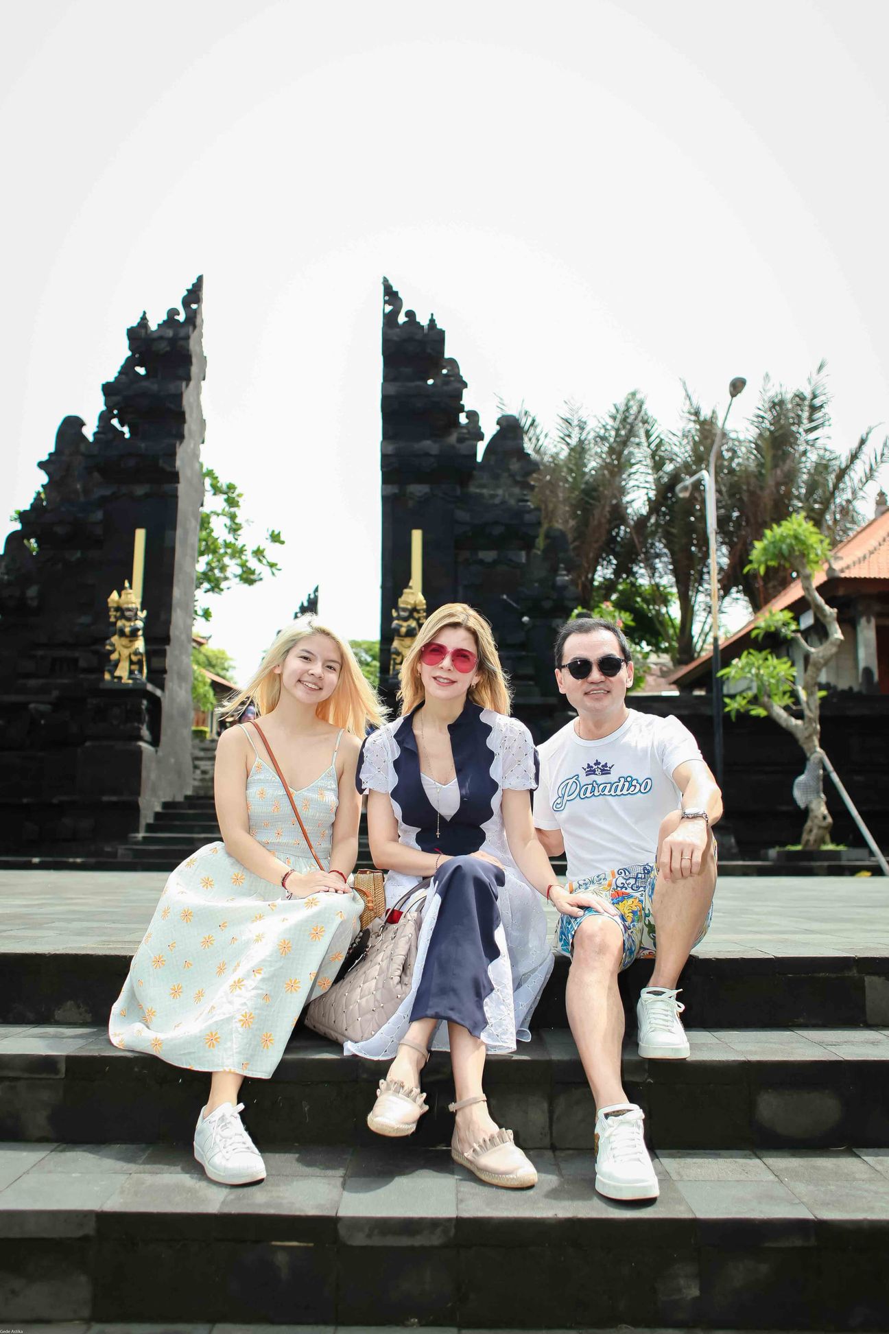Three travellers pose together at a temple and coastal viewpoint in Bali