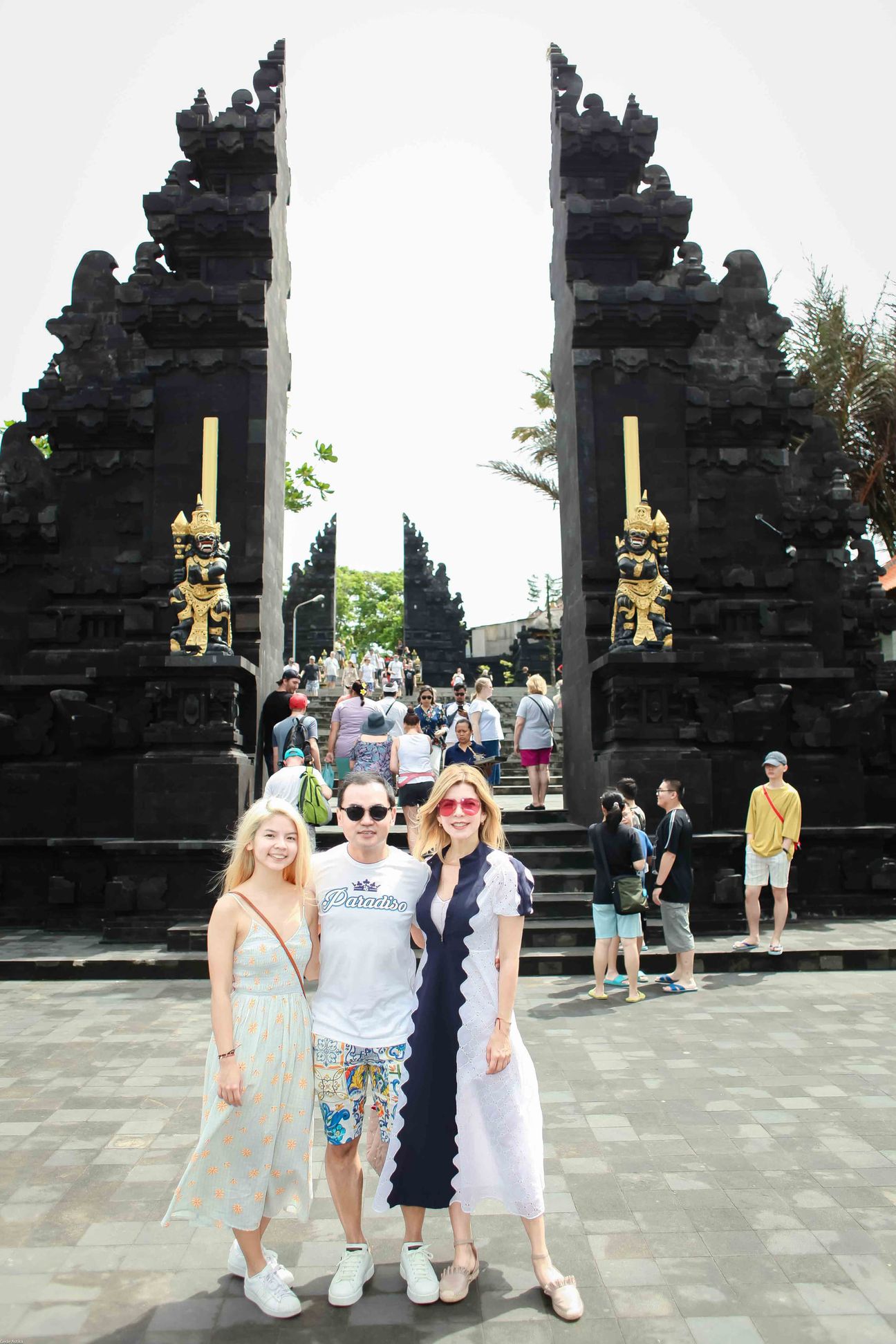 Three travellers pose together at a temple and coastal viewpoint in Bali