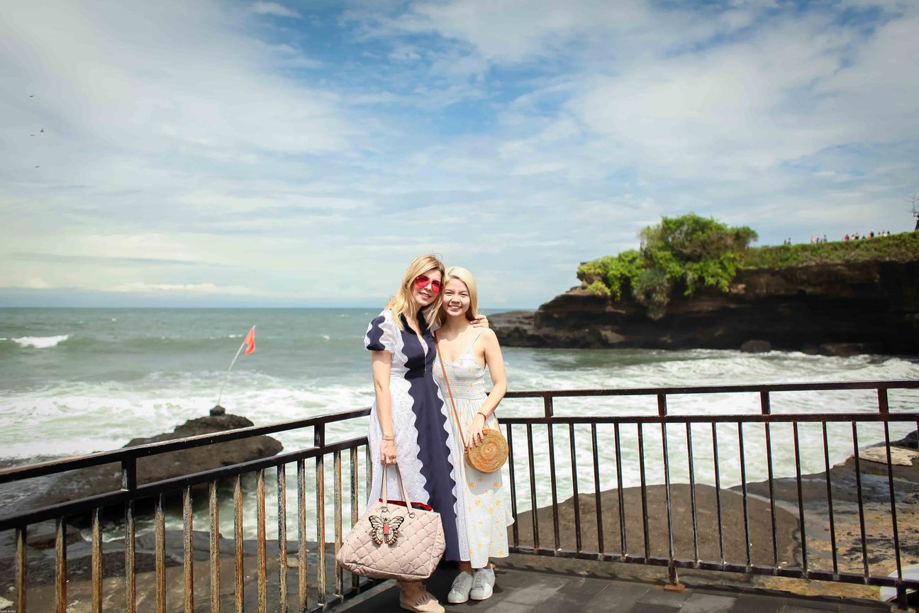 Three travellers pose together at a temple and coastal viewpoint in Bali