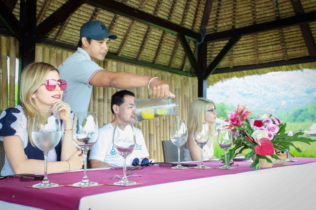 Guests share a meal in an open pavilion overlooking rice fields