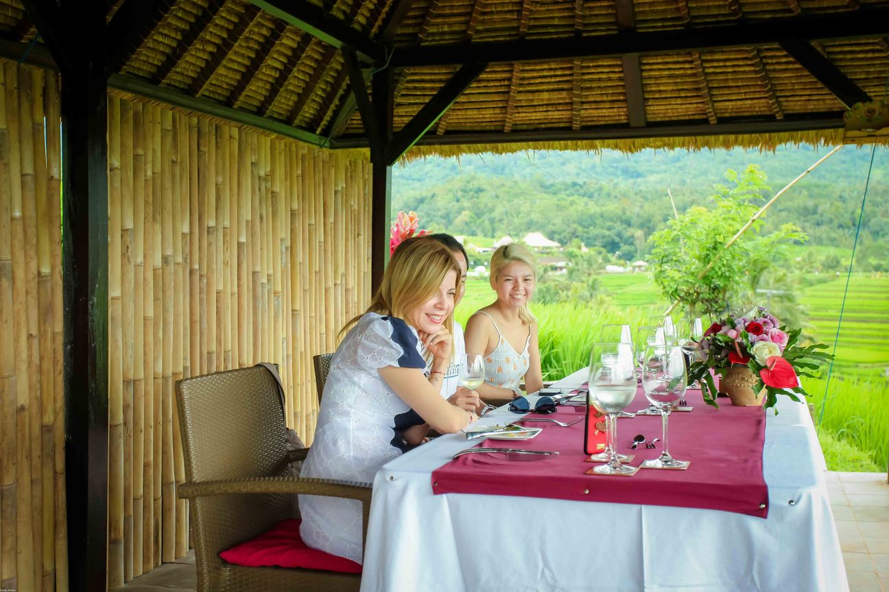 Guests share a meal in an open pavilion overlooking rice fields