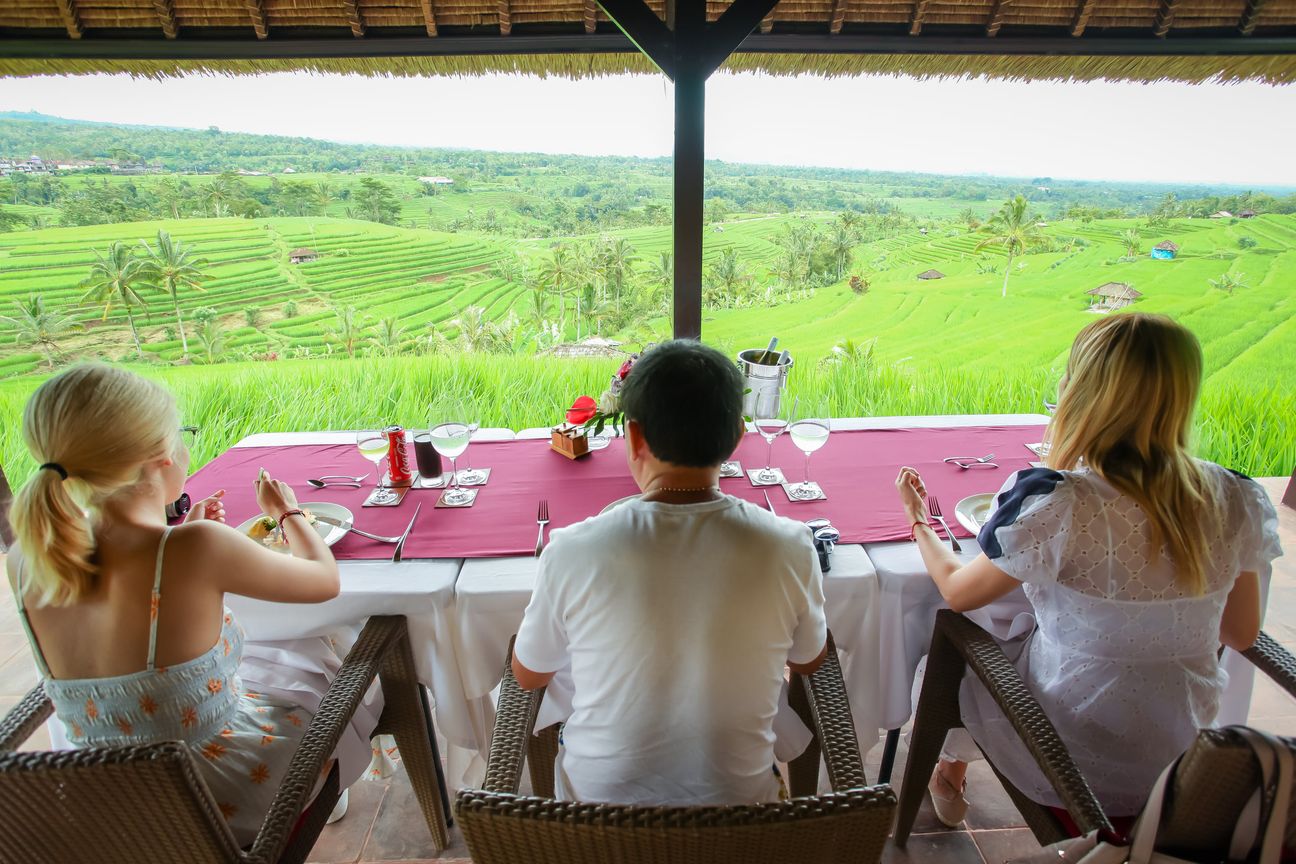 Guests share a meal in an open pavilion overlooking rice fields