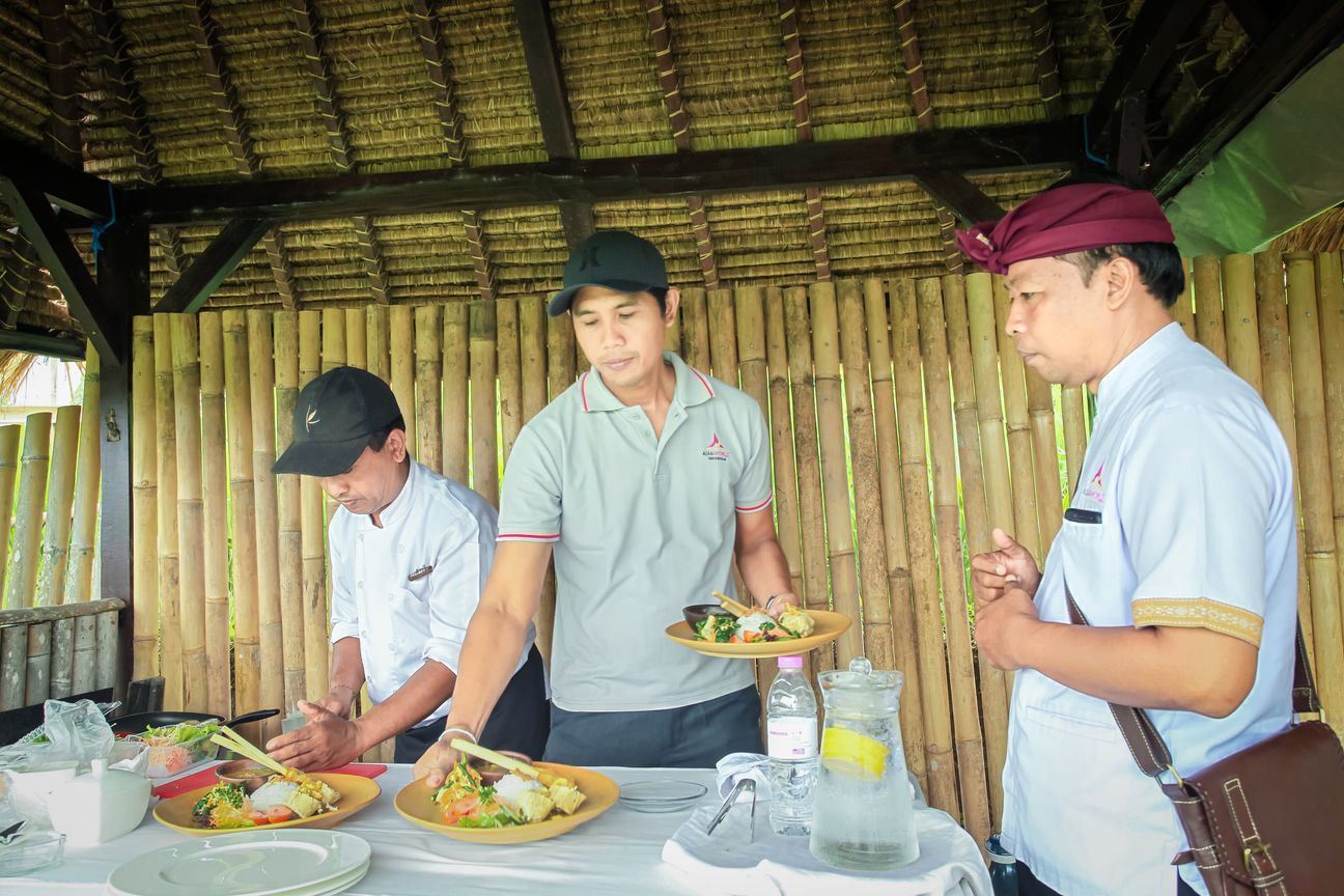 Guests share a meal in an open pavilion overlooking rice fields