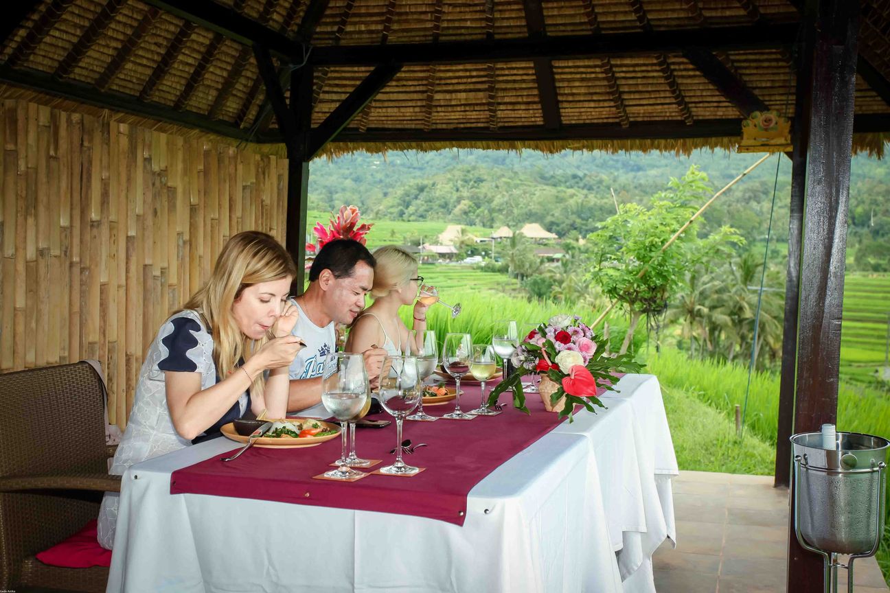 Guests share a meal in an open pavilion overlooking rice fields