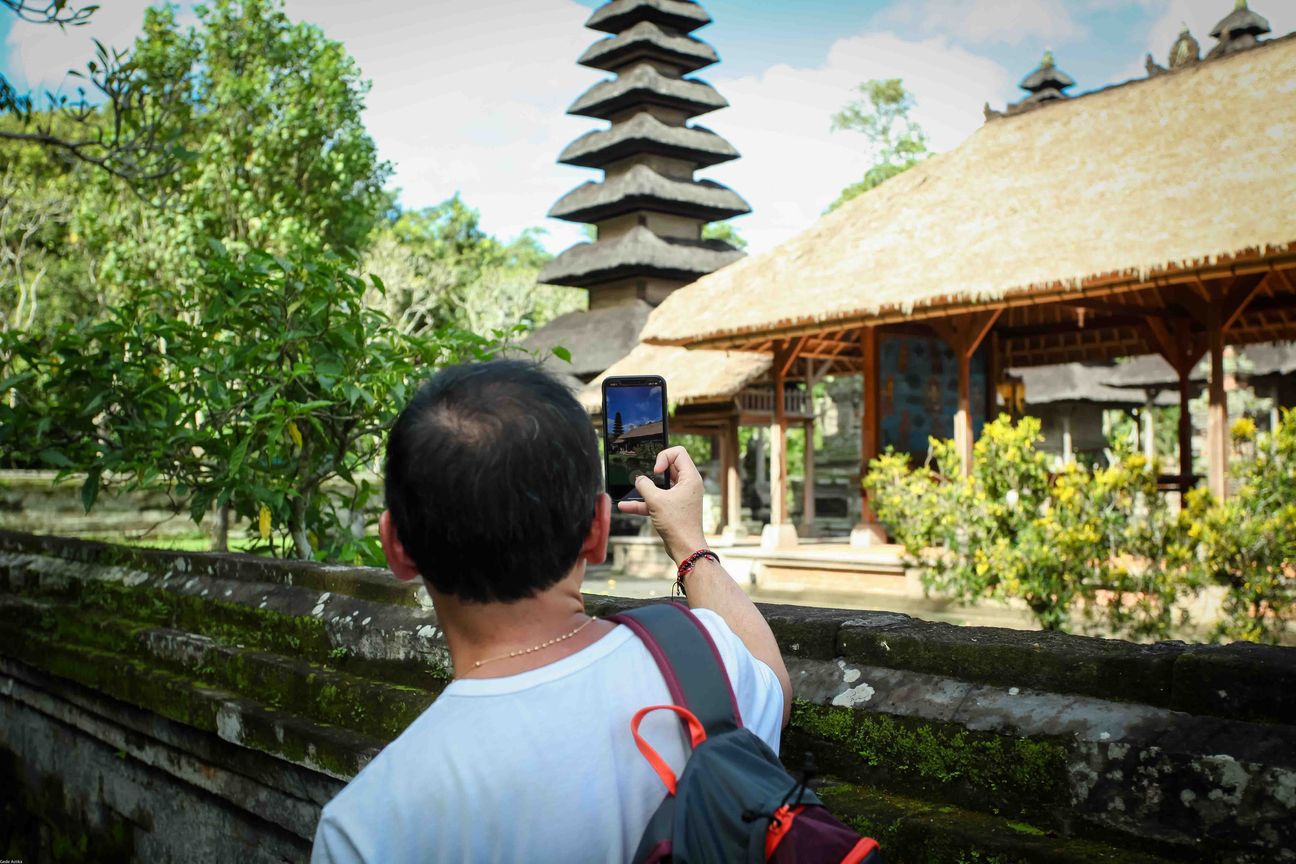 A visitor walks through a traditional Balinese temple complex