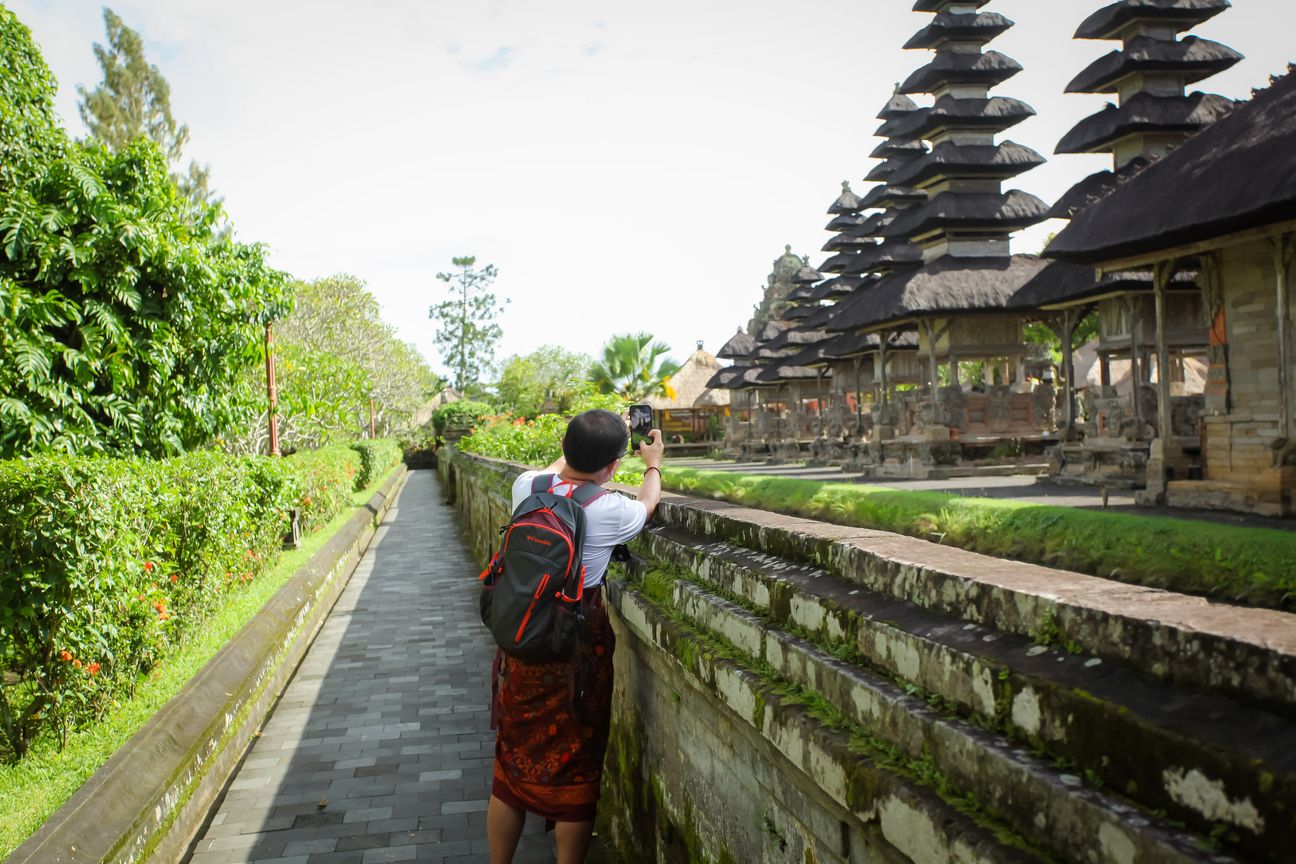 A visitor walks through a traditional Balinese temple complex