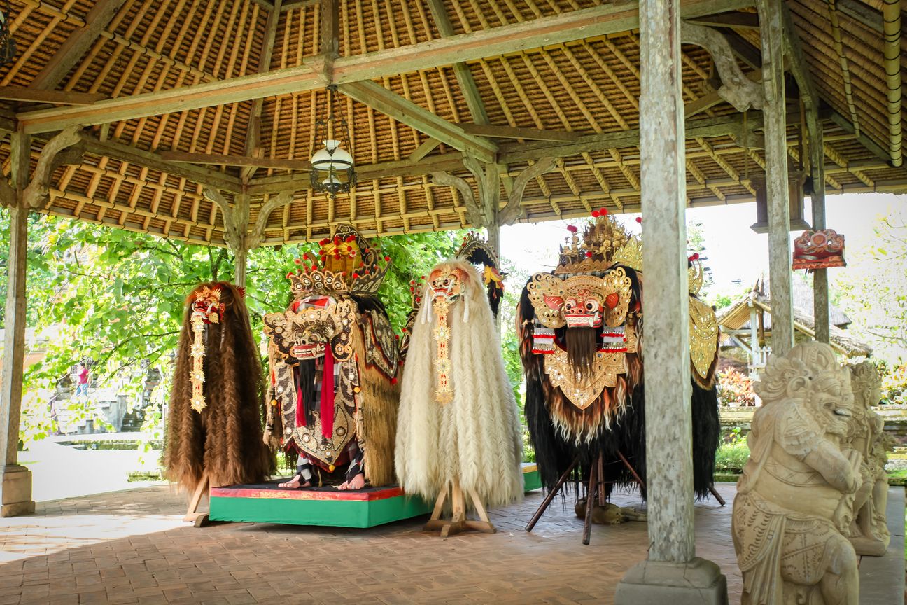 Ceremonial Barong figures stand beneath an open pavilion