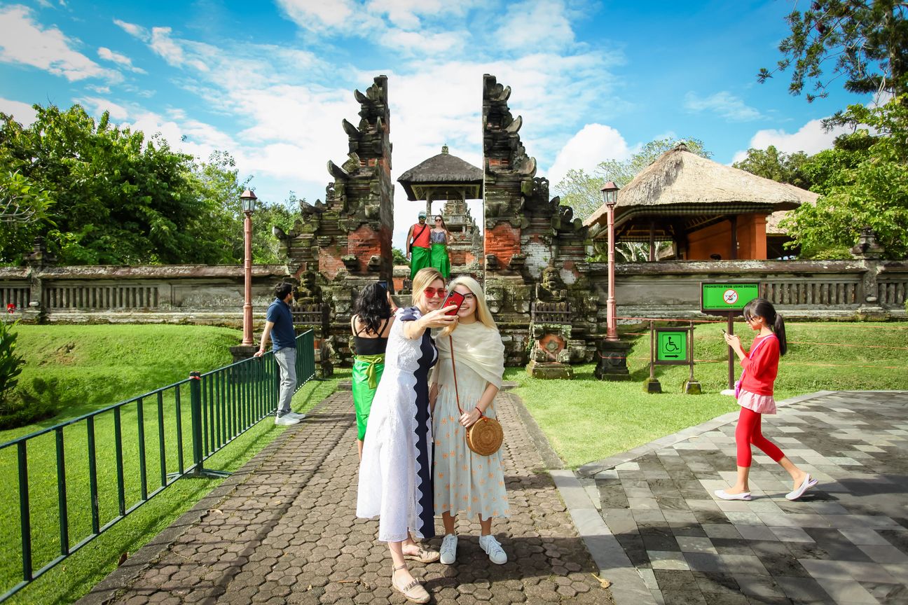 Travellers take photographs together in a Balinese temple garden
