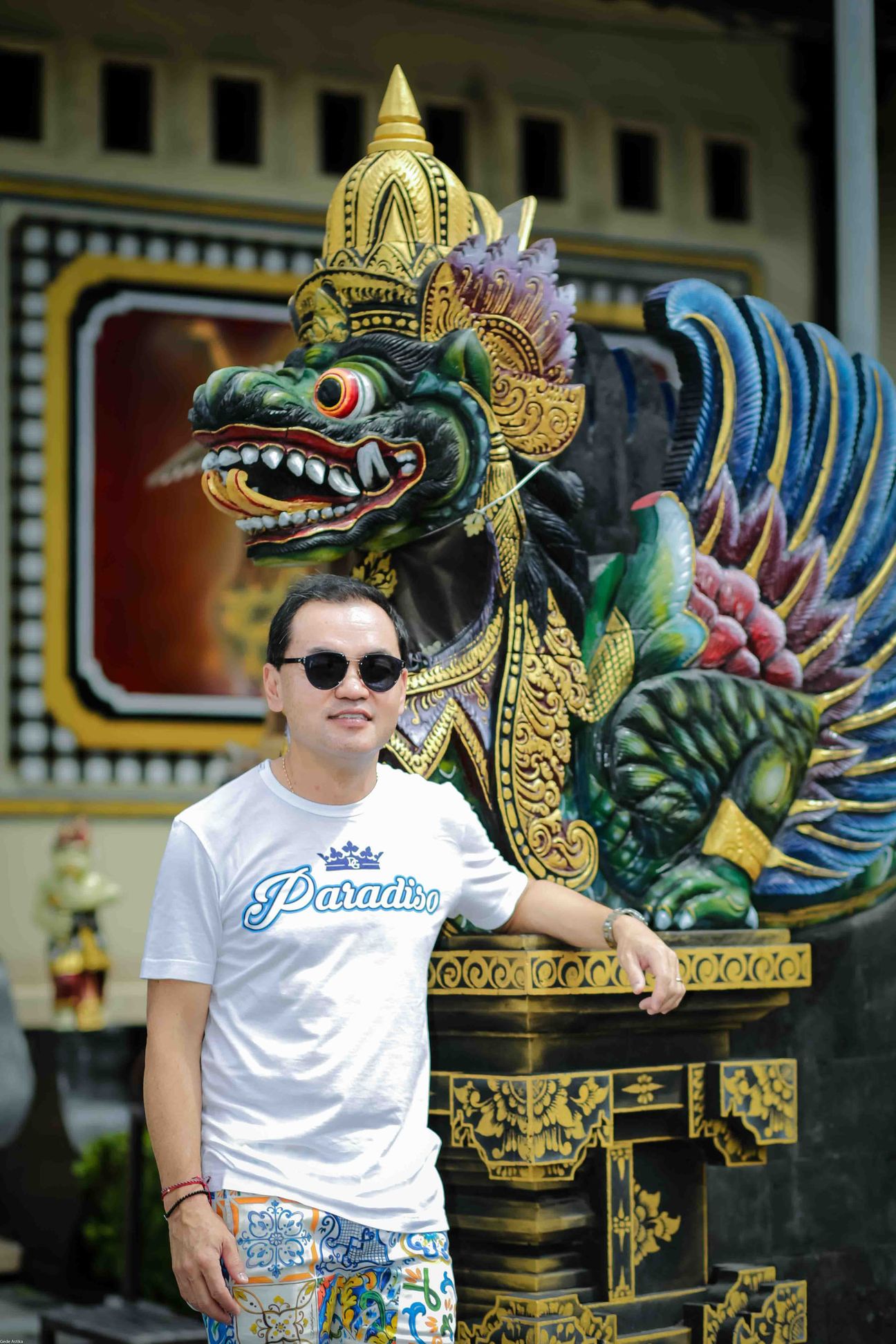 A traveller poses beside a colourful carved guardian figure
