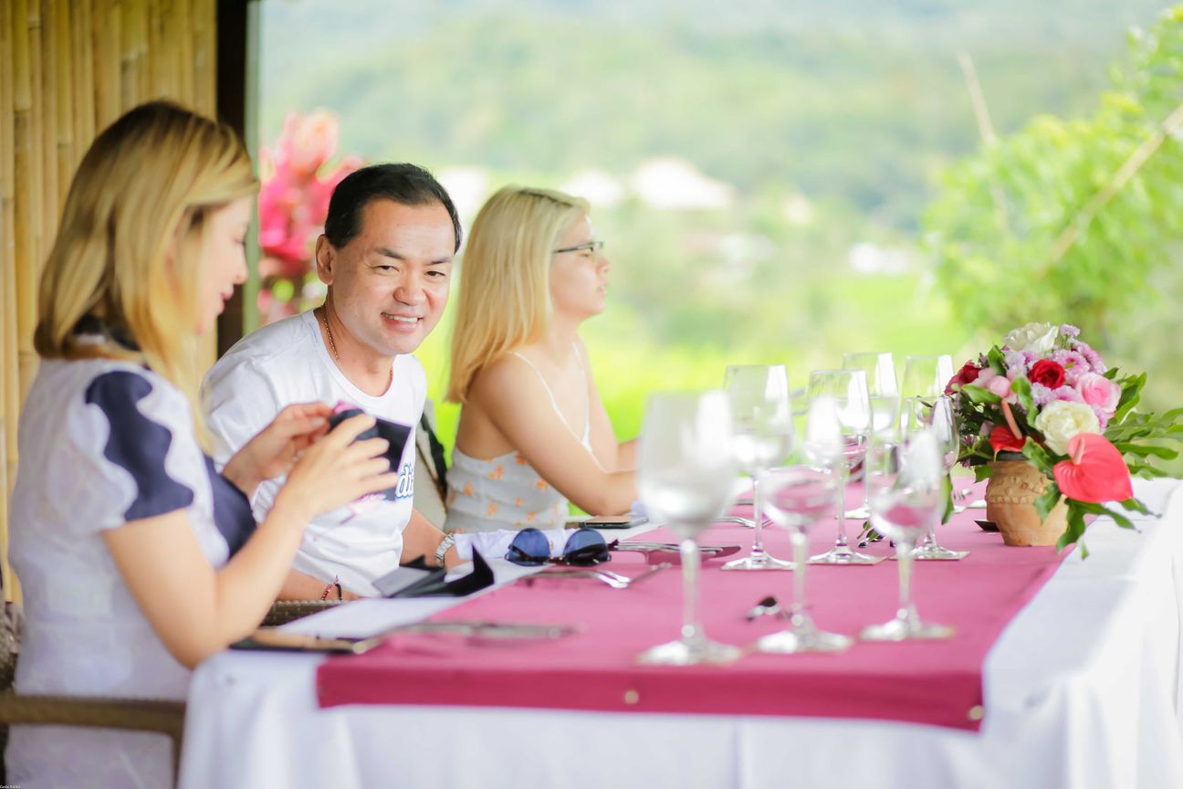 Travellers talk and eat around a table overlooking rice terraces