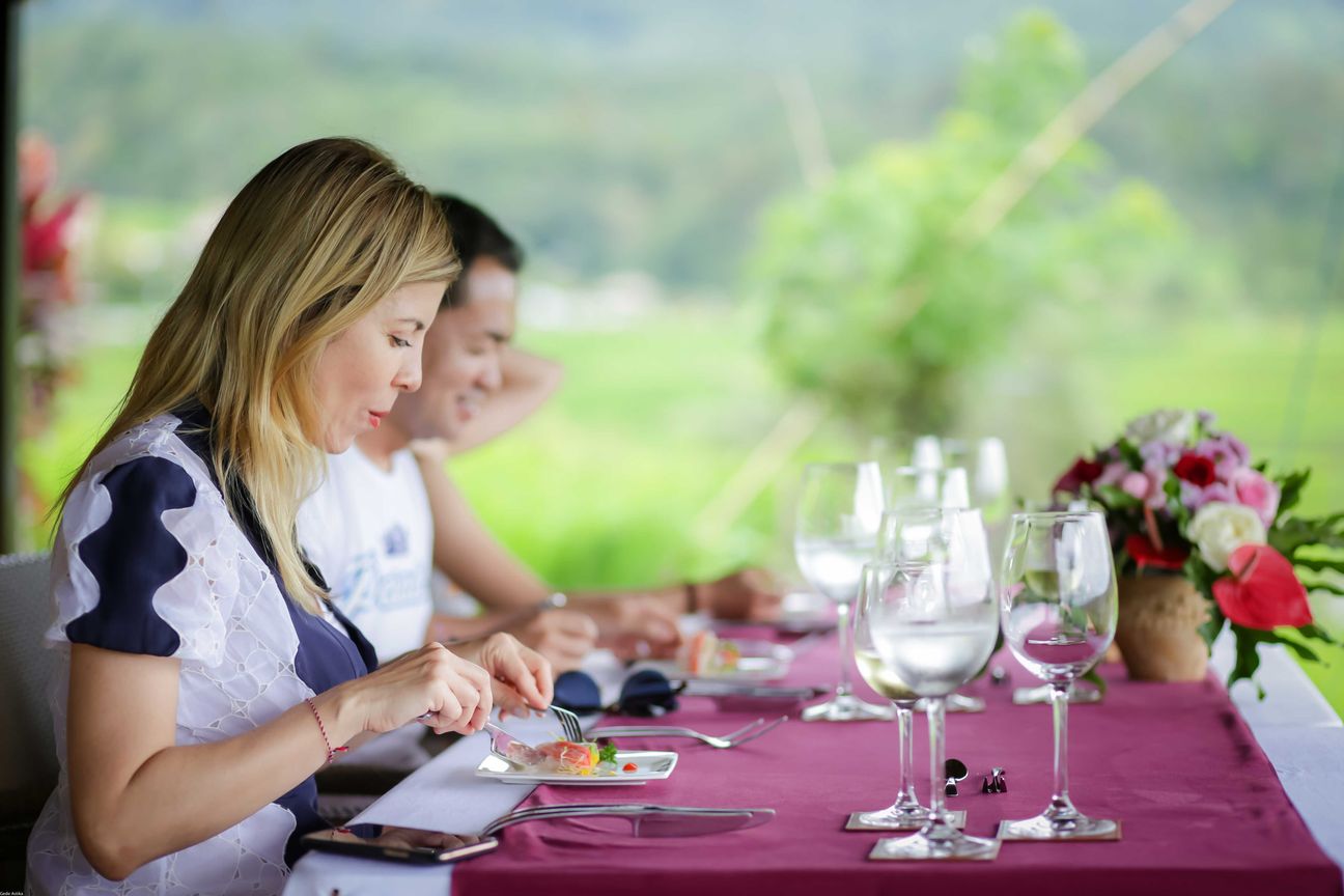 Travellers talk and eat around a table overlooking rice terraces