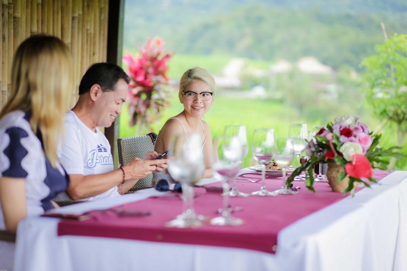 Travellers talk and eat around a table overlooking rice terraces