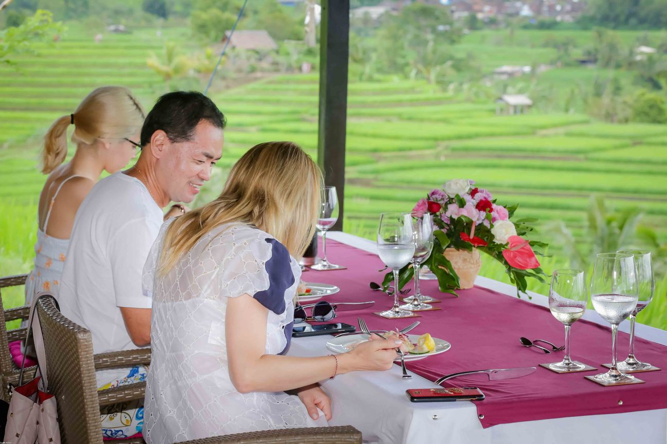 Travellers talk and eat around a table overlooking rice terraces