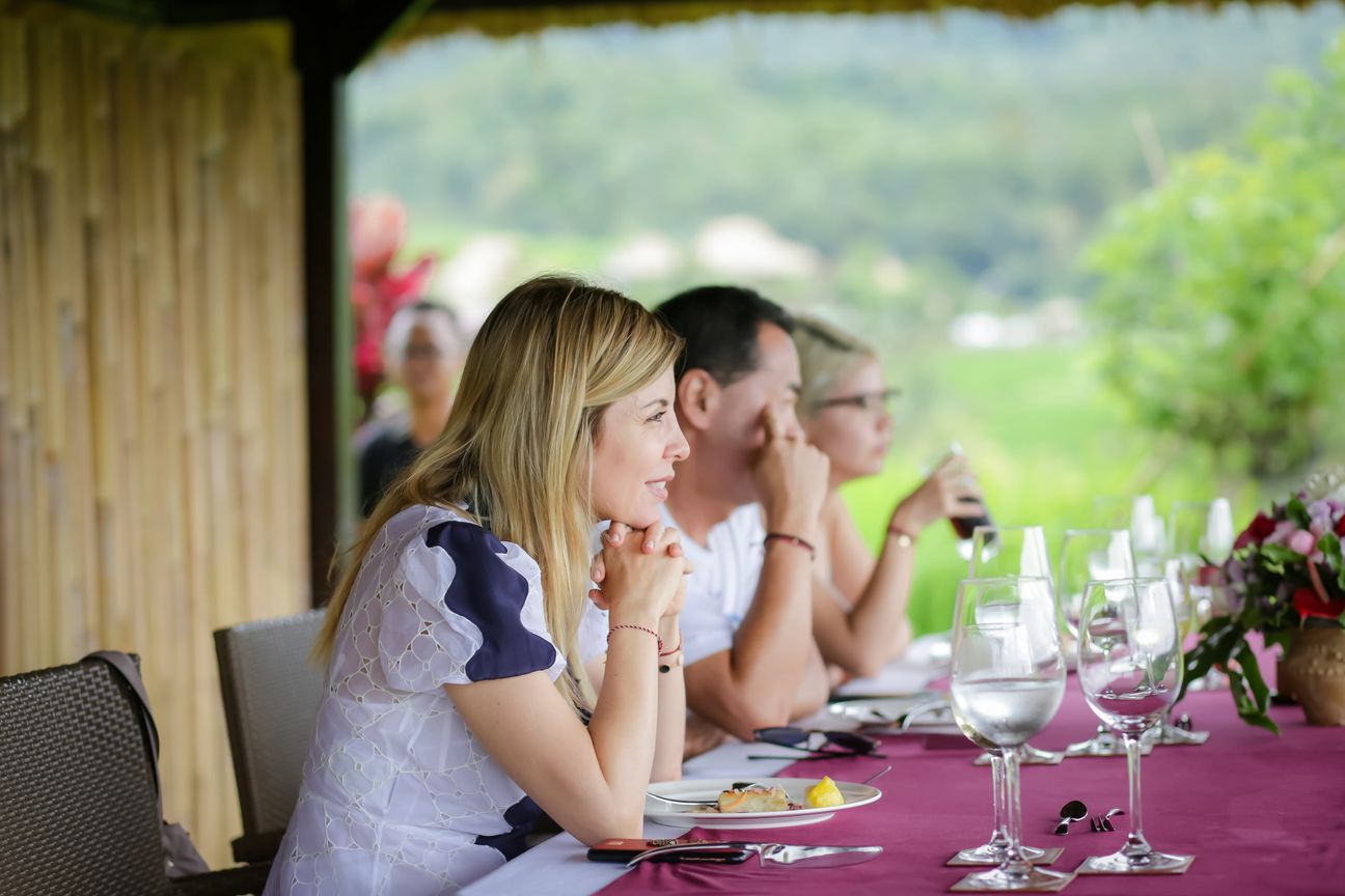 Travellers talk and eat around a table overlooking rice terraces