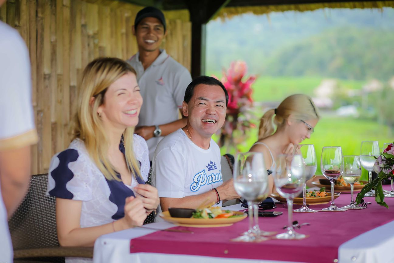 Travellers talk and eat around a table overlooking rice terraces