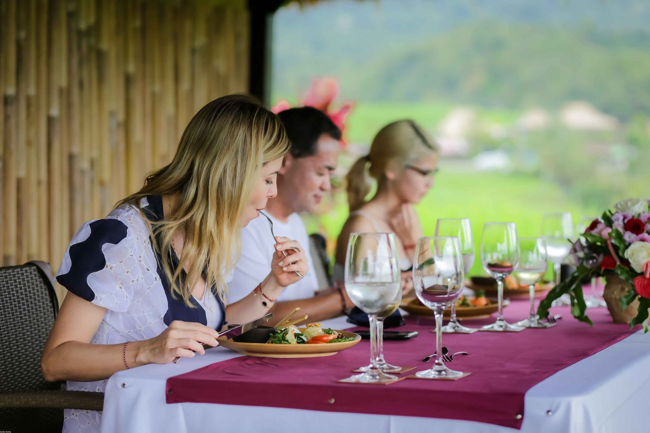 Travellers talk and eat around a table overlooking rice terraces