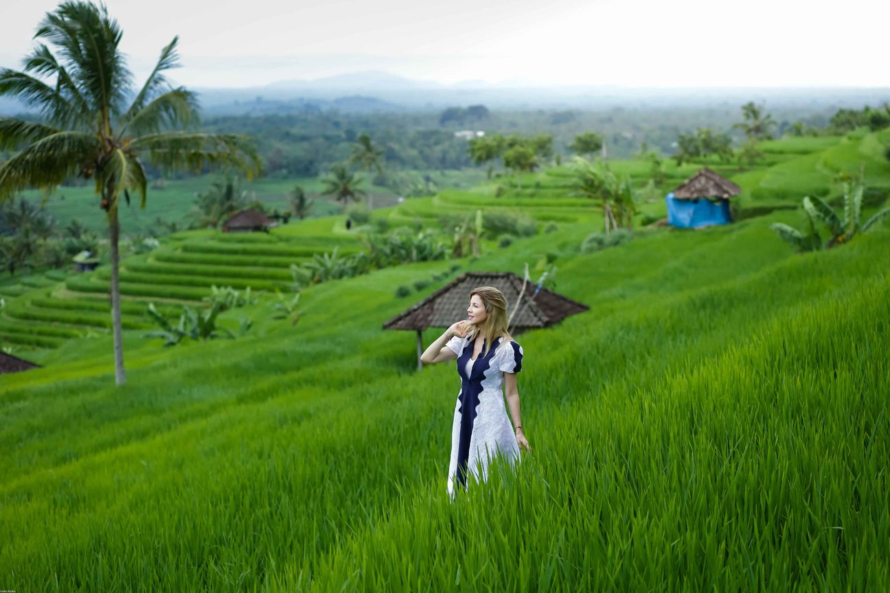 Travellers pose among layered green rice fields in Bali