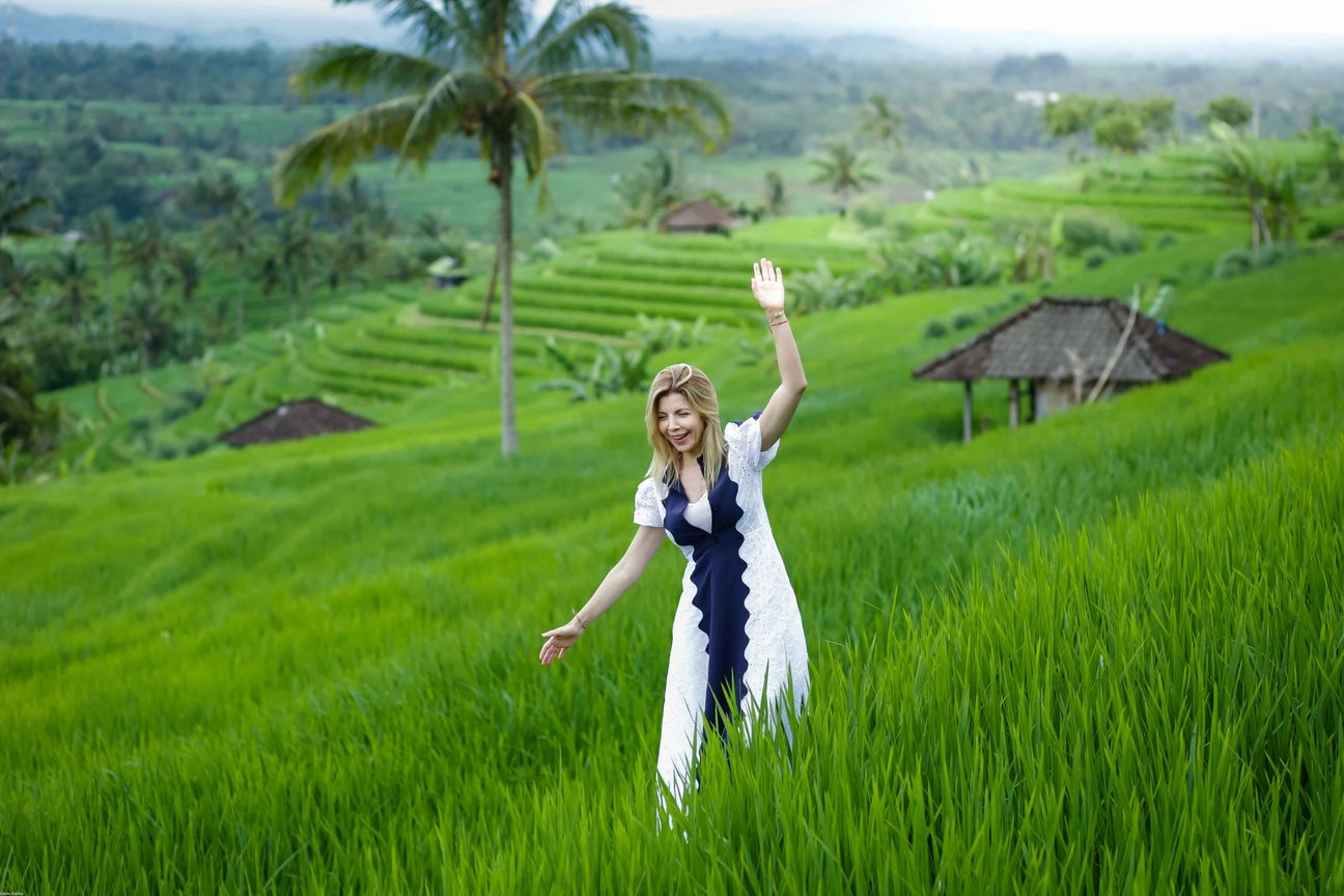 Travellers pose among layered green rice fields in Bali