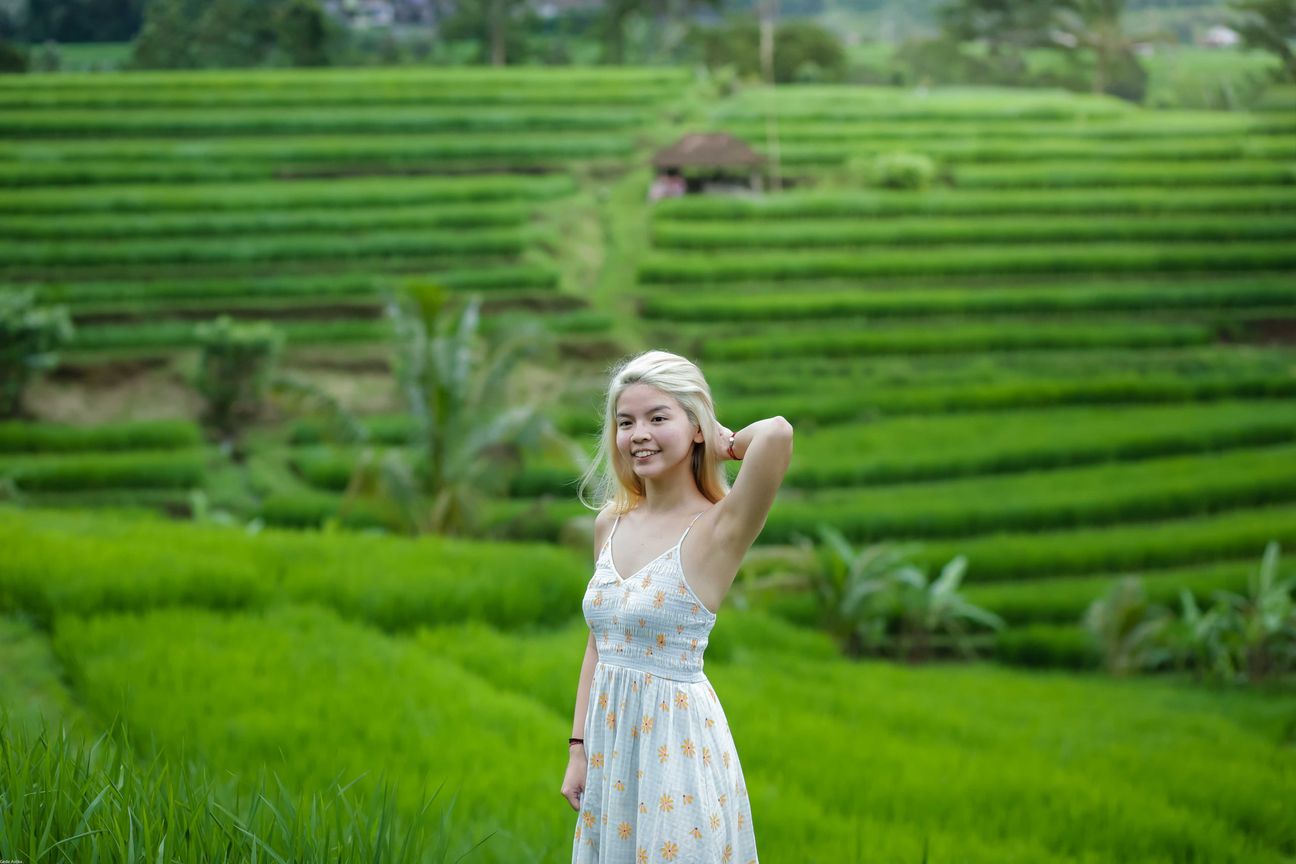Travellers pose among layered green rice fields in Bali