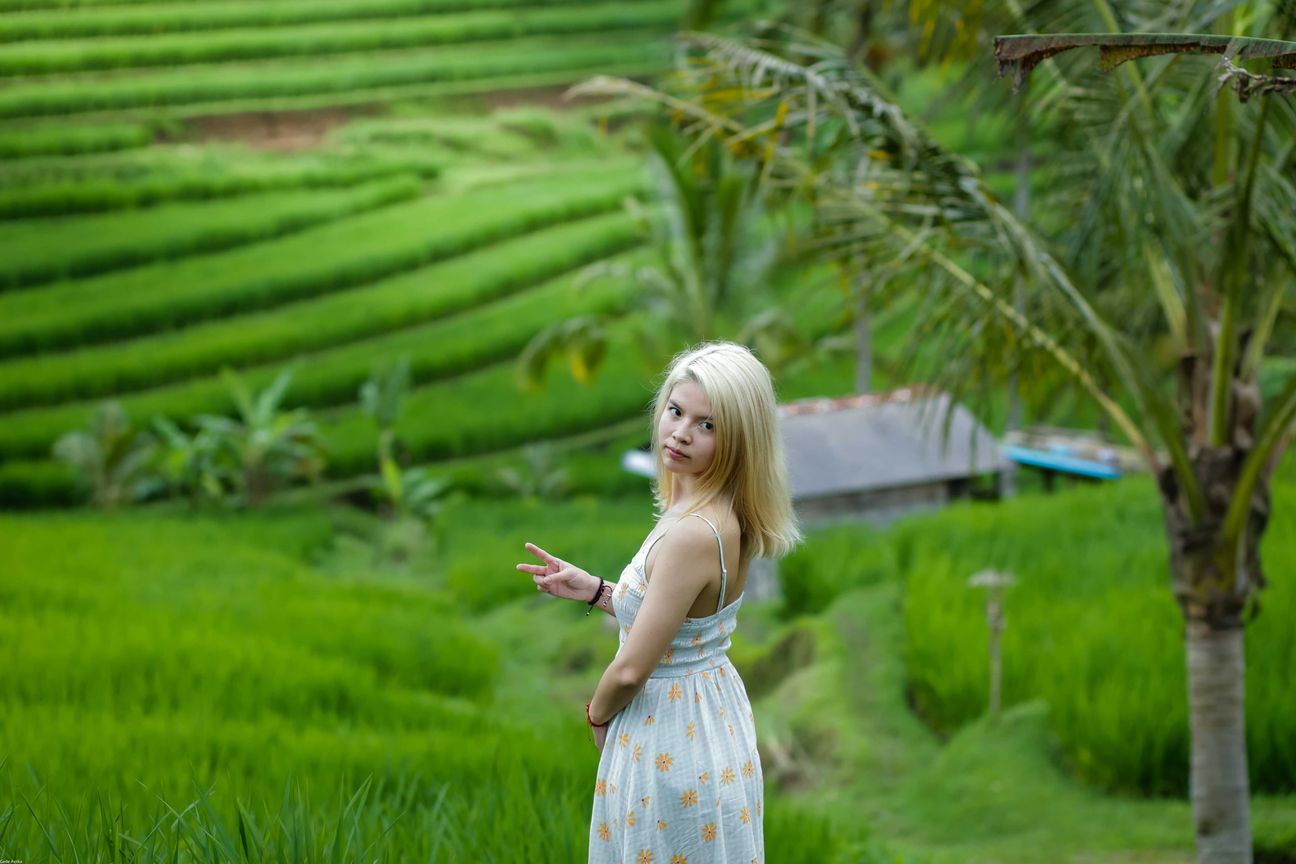 Travellers pose among layered green rice fields in Bali