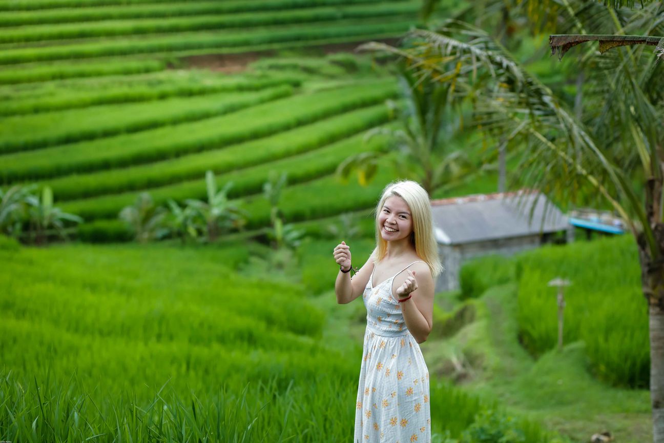 Travellers pose among layered green rice fields in Bali
