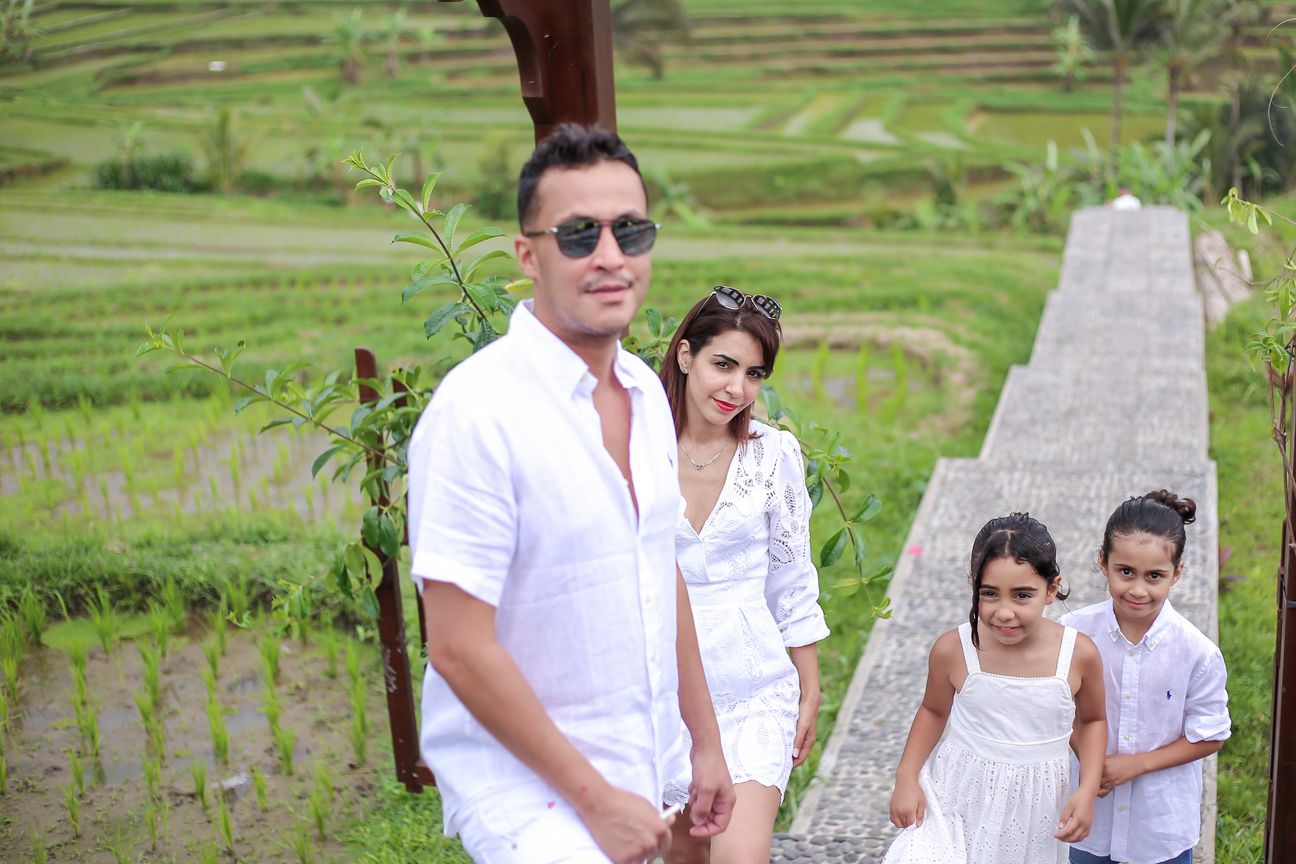 A family dressed in white walk the paths between the rice terraces