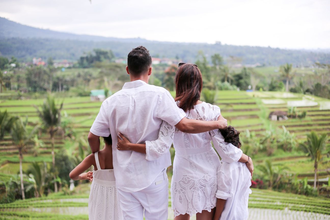 A family in white stand arm in arm, looking out over the rice terraces