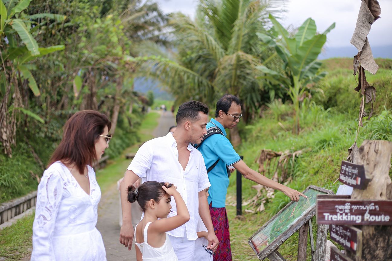 A family dressed in white walk the paths between the rice terraces