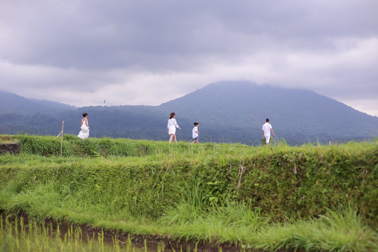 A family dressed in white walk the paths between the rice terraces
