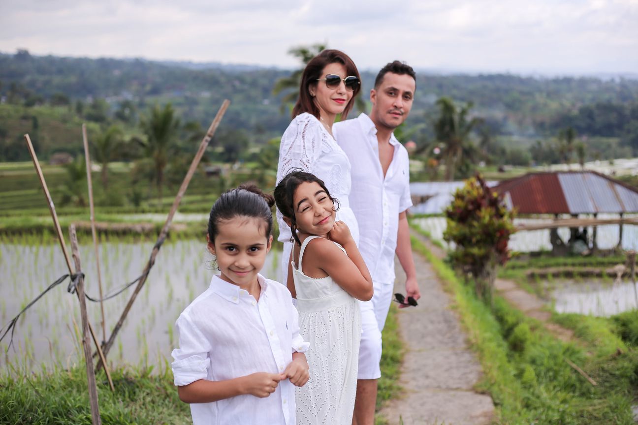 A family of four dressed in white pose together among the rice terraces