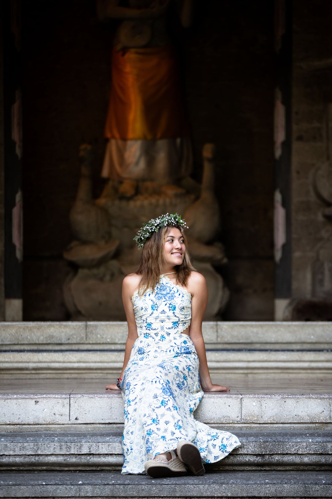 A woman in a floral dress poses in the shade of a tropical Balinese garden