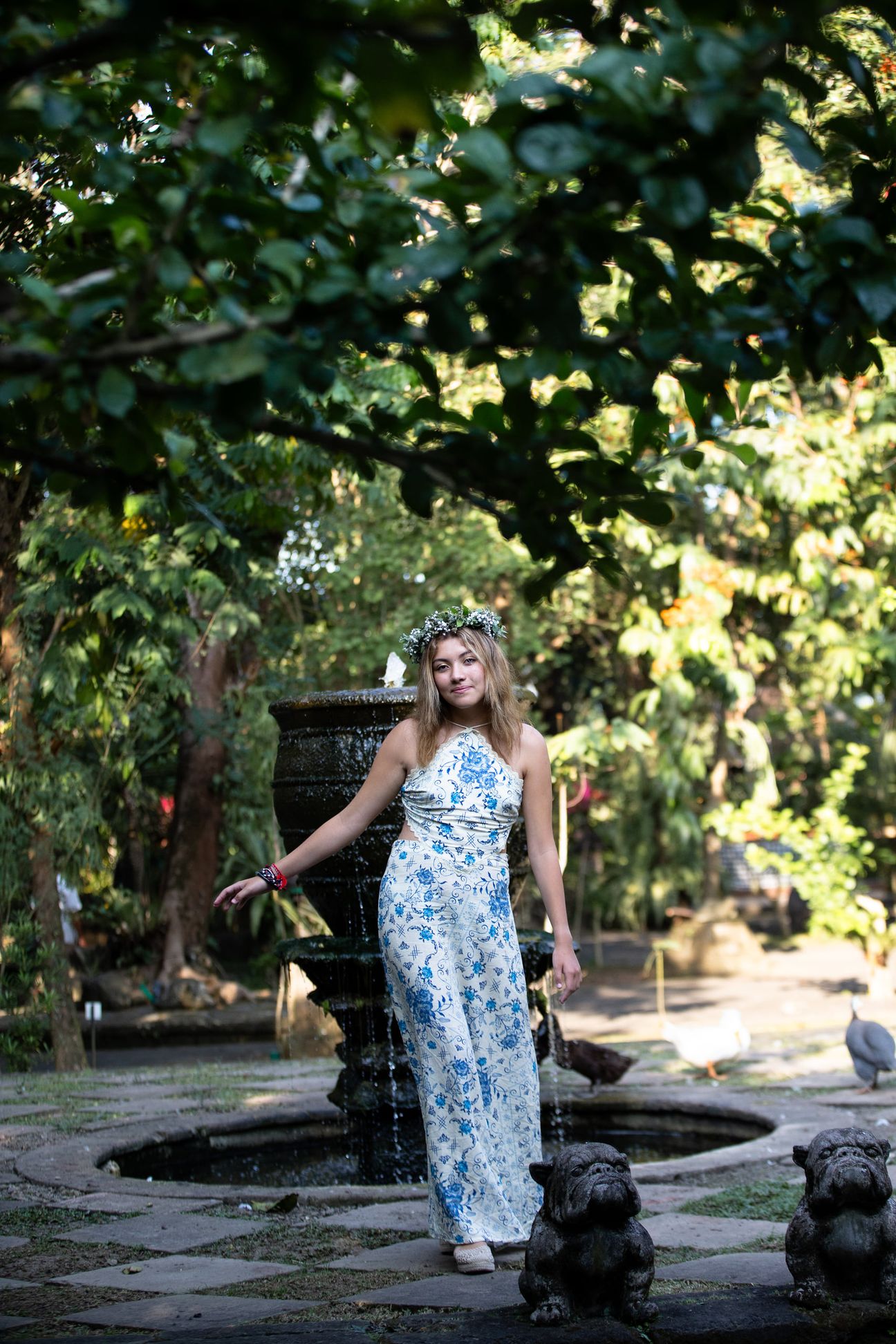 A woman in a floral dress poses in the shade of a tropical Balinese garden